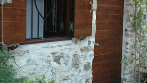 Ein Steinhaus mit Holztür und Fenster mit Fensterläden.