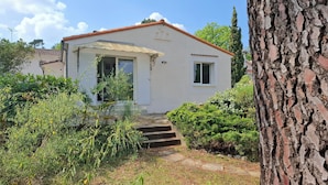 A white house with a red roof, a small window, and a door. There is a stone pathway leading to the entrance. - Architect-designed villa for 8 people close to the beach (Saint-Palais-Sur-Mer)