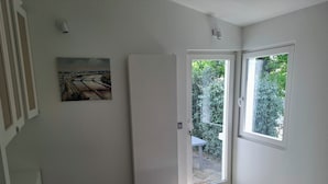 A bedroom with a bed, a door leading to a balcony, a painting on the wall, and a window. - Architect-designed villa for 8 people close to the beach (Saint-Palais-Sur-Mer)