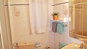 Un baño con inodoro, bidé, lavamanos y zona de ducha.