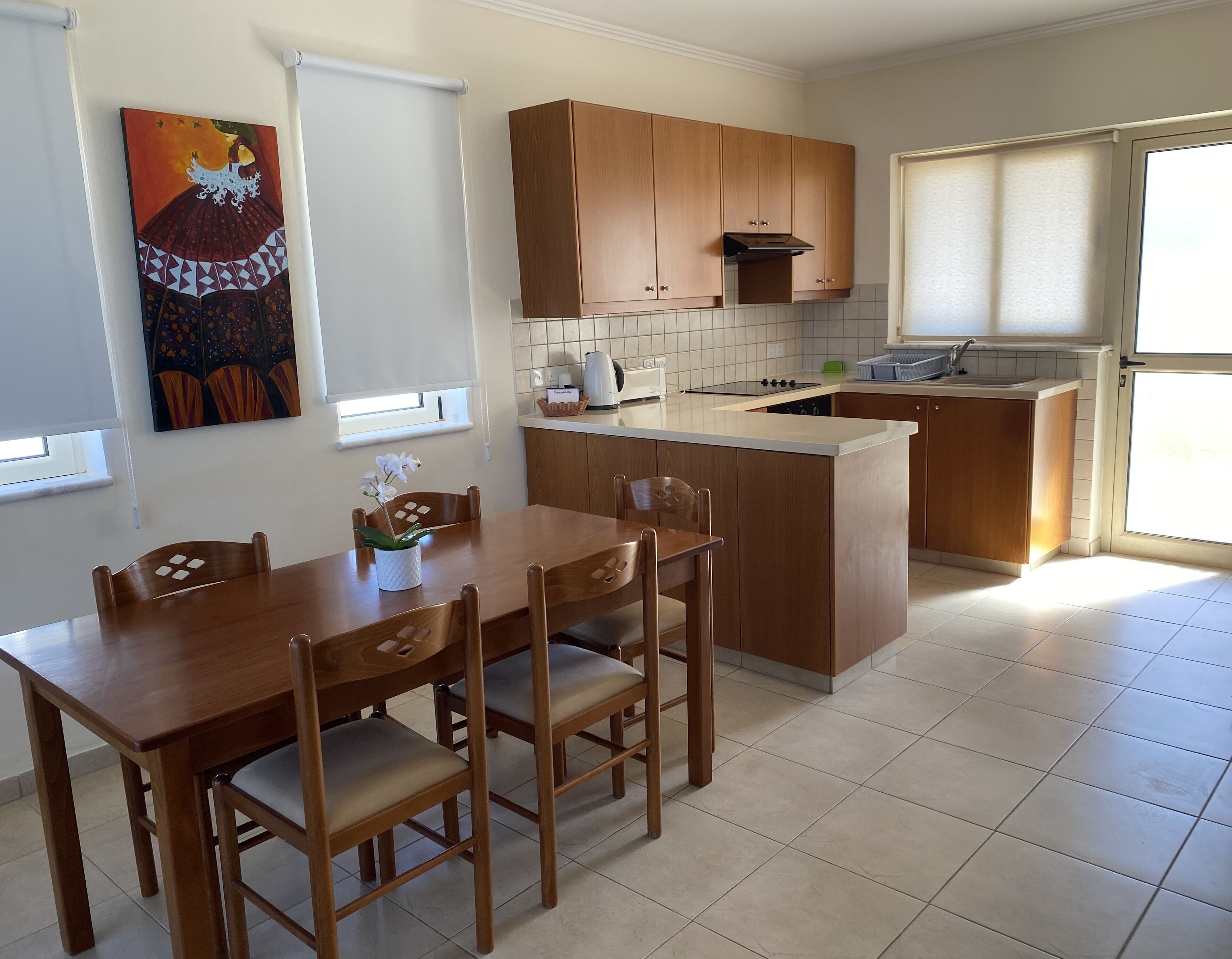 A compact kitchen with wooden cabinets, a dining table with chairs, and a small island.
