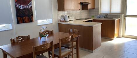A compact kitchen with wooden cabinets, a dining table with chairs, and a small island.