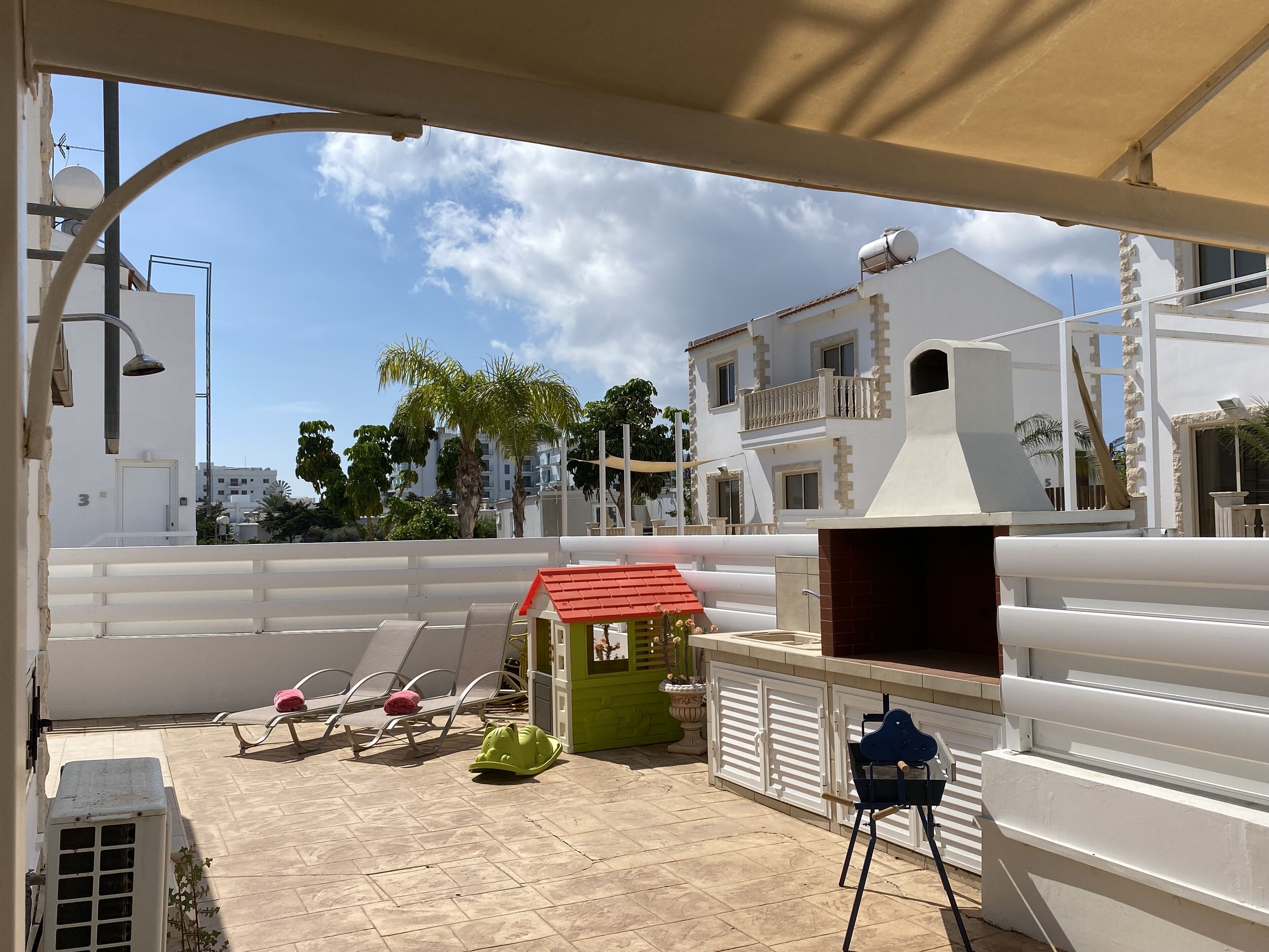 A rooftop terrace with lounge chairs, a barbecue grill, and a small garden area.
