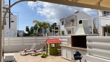 A rooftop terrace with lounge chairs, a barbecue grill, and a small garden area.