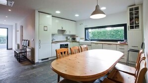 Een moderne keuken met witte kasten, een houten eettafel en een groot raam.