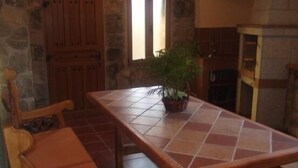 Una stanza accogliente con parete in pietra, porta in legno e un tavolo piastrellato con una pianta in vaso.