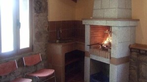 Una camera rustica con camino in pietra, una finestra e due poltrone.