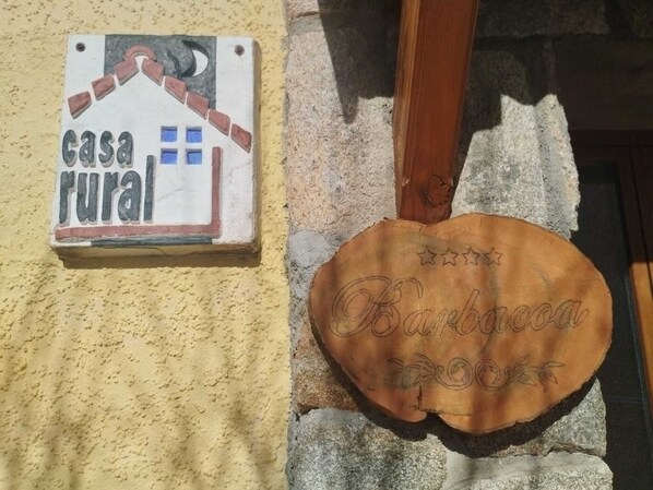 A sign reading "casa rural" and a wooden plaque with "Barbacoa" engraved on it.