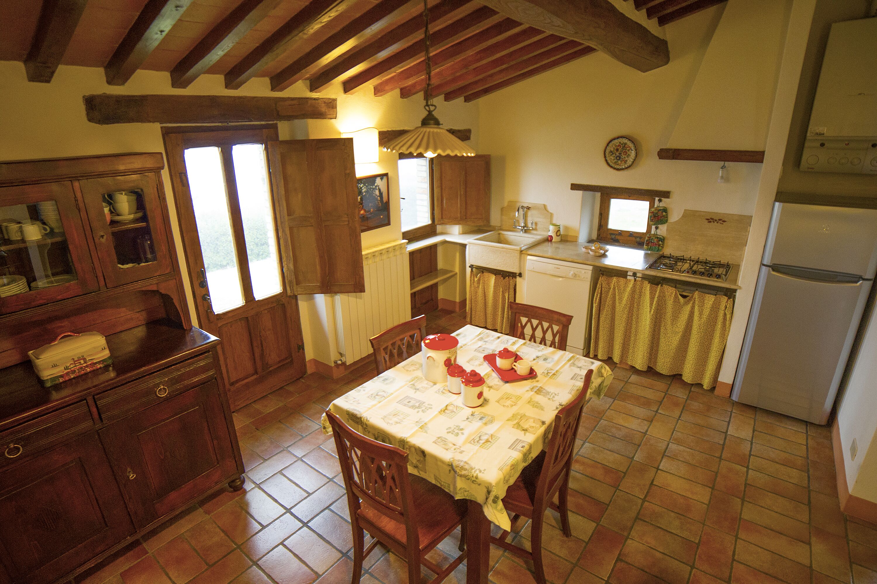 Una cocina rústica con armarios de madera, una mesa de comedor con sillas, una estufa y un refrigerador.