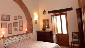 Een slaapkamer met een bed, een dressoir, een spiegel en een deur.