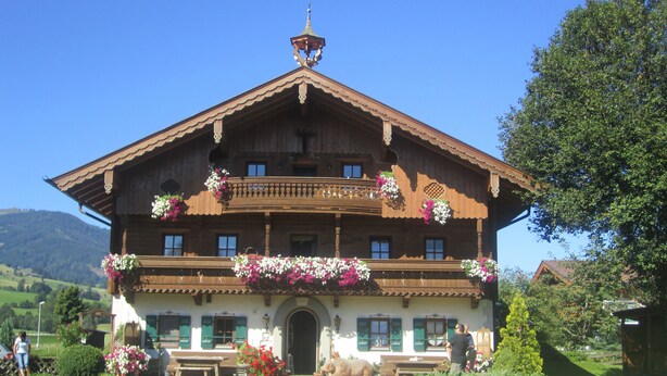 Un bâtiment traditionnel en bois, doté d’un balcon, d’une porte d’entrée et d’un petit jardin.