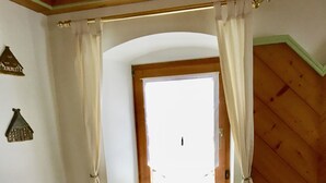 Une pièce chaleureuse avec un banc en bois, une fenêtre avec des rideaux et un objet décoratif fixé au mur.