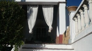 A white staircase leading to a balcony with white curtains.