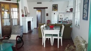 A spacious living area with a dining table, chairs, a sofa, and a kitchen in the background.