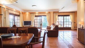 A spacious living room with a dining area, large windows, and a television.