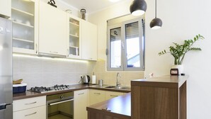 Eine moderne Küche mit weißen Schränken, einer Holzarbeitsplatte, einem eingebauten Backofen, einer Spüle und Pendelleuchten.