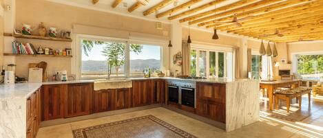 A spacious kitchen with wooden beams, a large island, and a view of the outdoors.