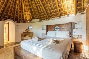 Una habitación con una cama, cabecero de madera, una mesita de noche y una pequeña mesa.