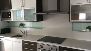 Eine moderne Küche mit Edelstahlgeräten, einer Glasrückwand und einem eingebauten Backofen.
