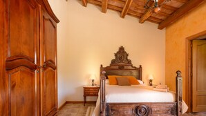 A bedroom with a wooden bed, a nightstand, a wardrobe, and a chandelier. - Self catering Can Salvà for 12 people (Vilobí d'Onyar)