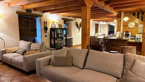 A cozy living room with a sofa set, wooden beams, a dining area, and a clock on the wall. - The Abode of Vadinia (Burón)