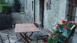 A stone building with a wooden table and chairs in the courtyard. - The Abode of Vadinia (Burón)