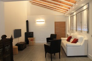 Ein modernes Wohnzimmer mit einem weißen Sofa, schwarzen Sesseln, einer Holzkommode und einem Kamin.