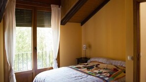 Een slaapkamer met een bed, nachtkastje en raam met gordijnen.