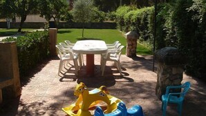 A patio with a round table and chairs, surrounded by greenery and a play area with a blue and yellow ride-on toy. - Country house (full rental) Ribera El Duero for 6 people + 2camas suppl. (Traspinedo)
