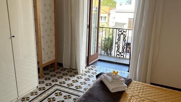 Een hotelkamer met een bed, een kledingkast, een klein tafeltje en uitzicht op het balkon.
