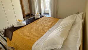 Een hotelkamer met een bed, een kledingkast, een spiegel en een raam met gordijnen.