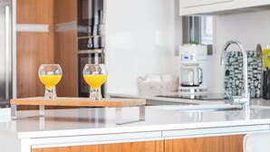 Una cucina moderna con due bicchieri di succo d'arancia su un vassoio di legno, un lavello in acciaio inossidabile e una macchina da caffè.