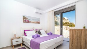 Una camera da letto con un letto, un comodino e un'ampia finestra vista su un paesaggio montano.