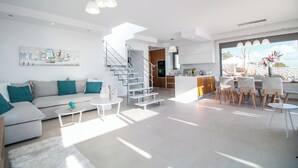 Un soggiorno moderno con un divano, un tavolino da caffè e una scala che conduce a una cucina.