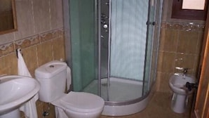 Une salle de bain avec une douche à parois de verre, des toilettes et un lavabo.