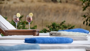 A hotel room with a bed, two glasses of pink drink with lemon slices, and blue towels. - DUNES Villa with Private pool for 6 (Naxos)