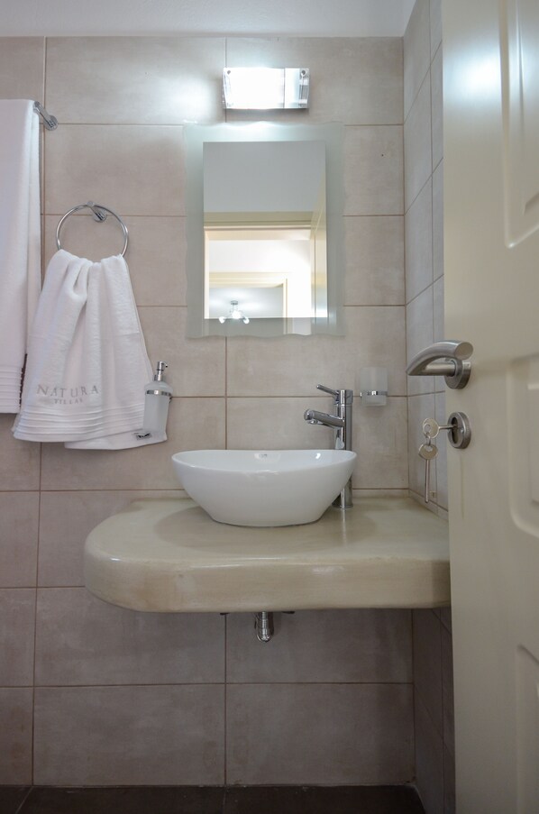 A bathroom with a white sink, a towel rack with a white towel, a mirror, and a light fixture above the mirror. - DUNES Villa with Private pool for 6 (Naxos)