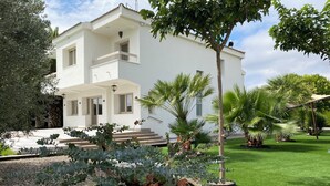 A modern two-story building with a balcony, surrounded by a well-maintained garden with various plants and a lawn. - Tranquility, calm and relax. (Olite)