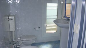 A bathroom with a toilet, sink, and a door with a window. - Apartment Lumia Bilo Mansard at the sea (Sciacca)
