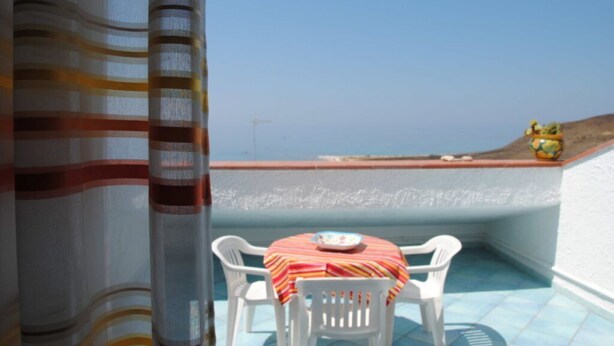 A balcony with a table and chairs, a view of the sea, and a decorative globe. - Apartment Lumia Bilo Mansard at the sea (Sciacca)