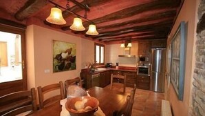Un tavolo da pranzo in legno con sedie, una ciotola di frutta e un quadro appeso al muro.