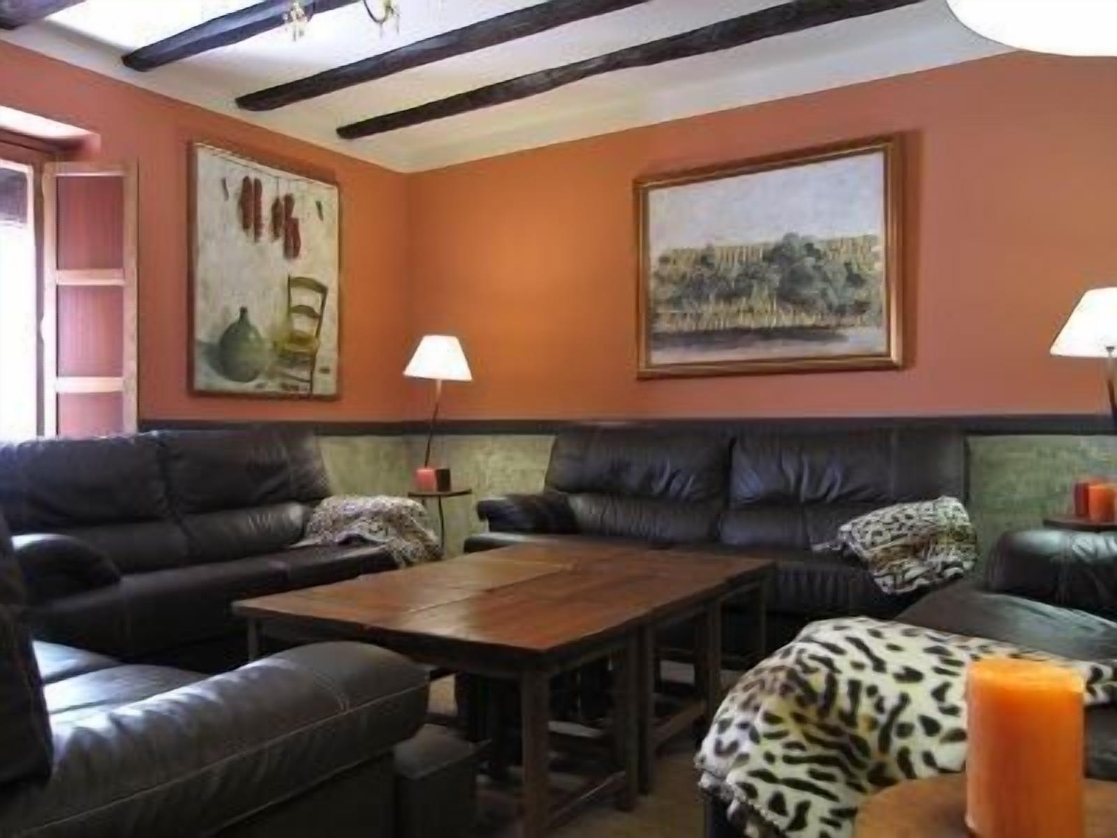 A living room with a dark brown sofa set, a wooden coffee table, and two wall-mounted lamps.