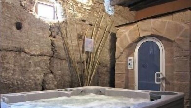 Una stanza con pareti in pietra, una vasca idromassaggio e una porta.