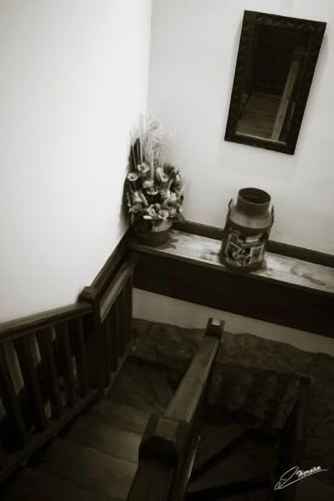 A staircase with a wooden handrail, a metal railing, and a small table with a vase and a candle holder.