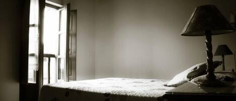 A dimly lit room with a bed, a lamp, and a window with curtains.
