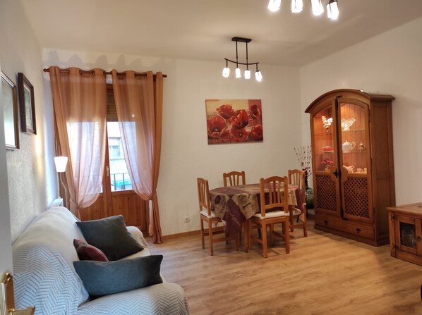 Una sala de estar acogedora con sofá, mesa de comedor de madera, sillas y un aparador.
