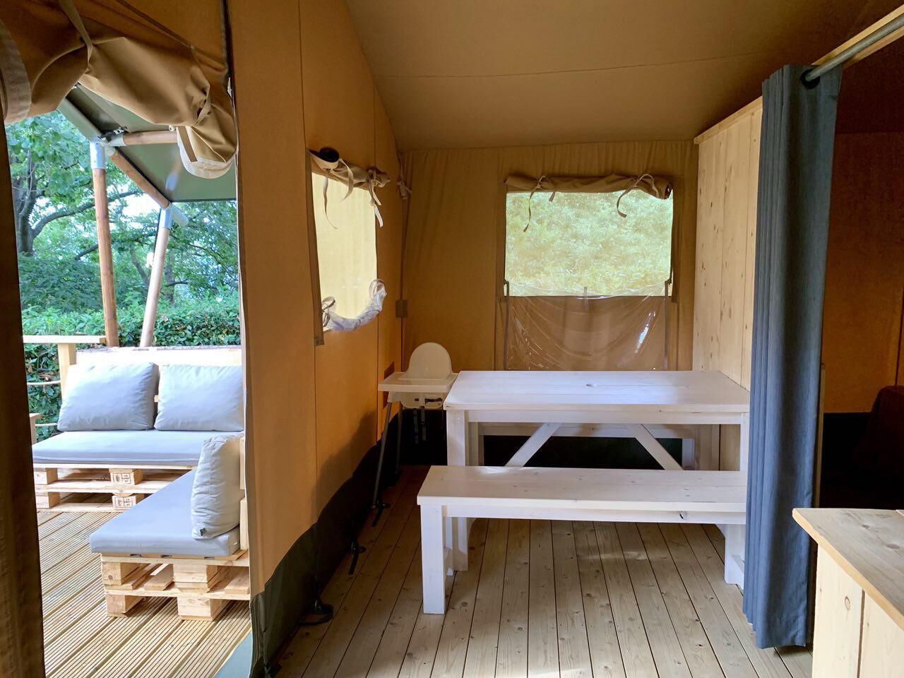 A wooden cabin interior with a wooden bench, a small table, and a cushioned seating area.