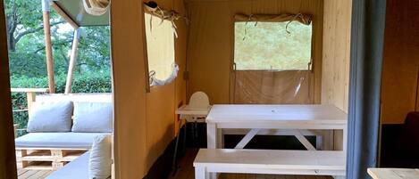 A wooden cabin interior with a wooden bench, a small table, and a cushioned seating area.
