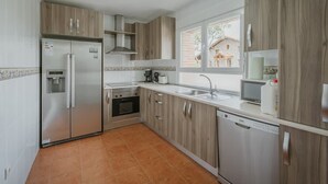 Una cocina con refrigerador, horno, pileta y lavavajillas.