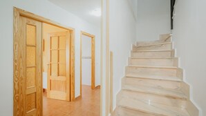 Una escalera de escalones de mármol que conduce a una plataforma, junto a una puerta de madera con paneles de vidrio.